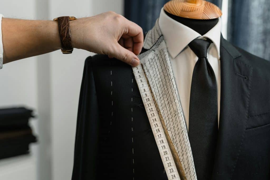 Tailor measuring a suit jacket for whisky tasting event elegance.
