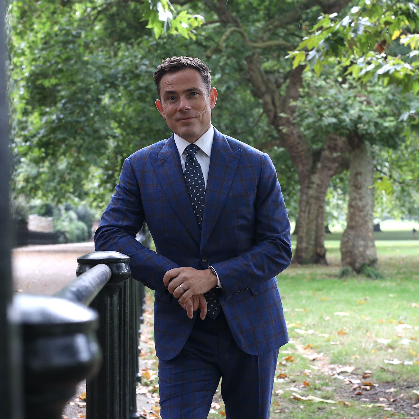 Man wearing a tailored single-breasted navy suit with a crisp white shirt and silk tie, ideal for business settings.