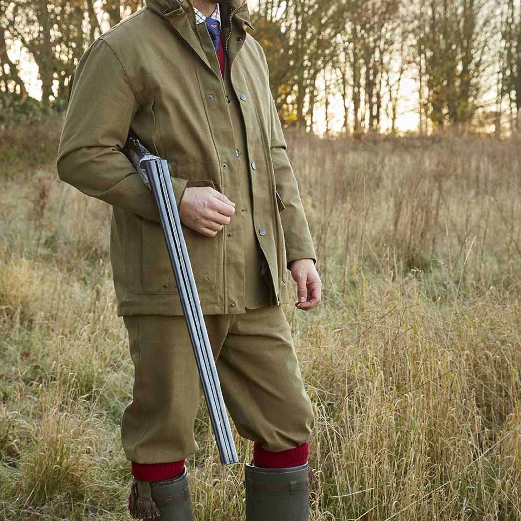 Man wearing water-resistant synthetic trousers in dark green for wet weather shooting.