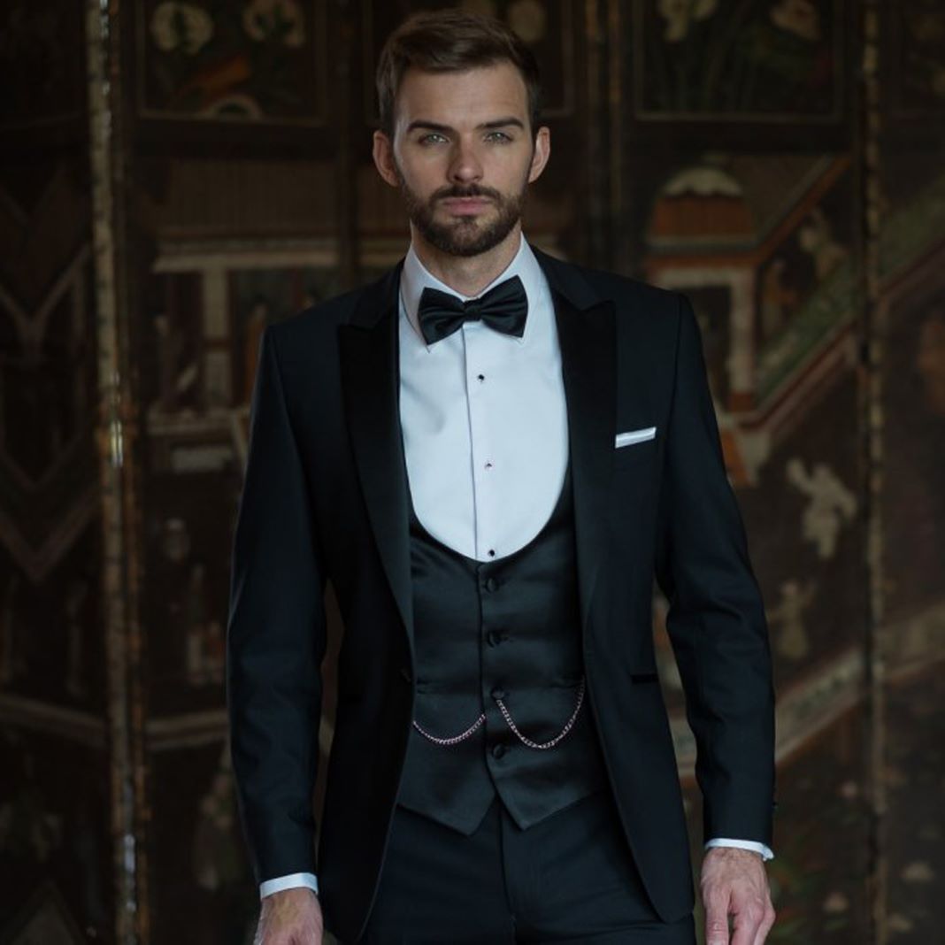 Classic black dinner suit with a single-button jacket and satin shawl lapel, styled with a bow tie.