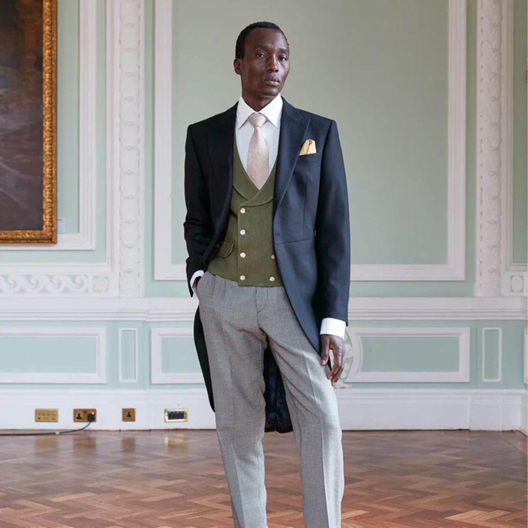 Groom in a navy morning suit with a cream waistcoat and pale pink tie, styled for a formal wedding