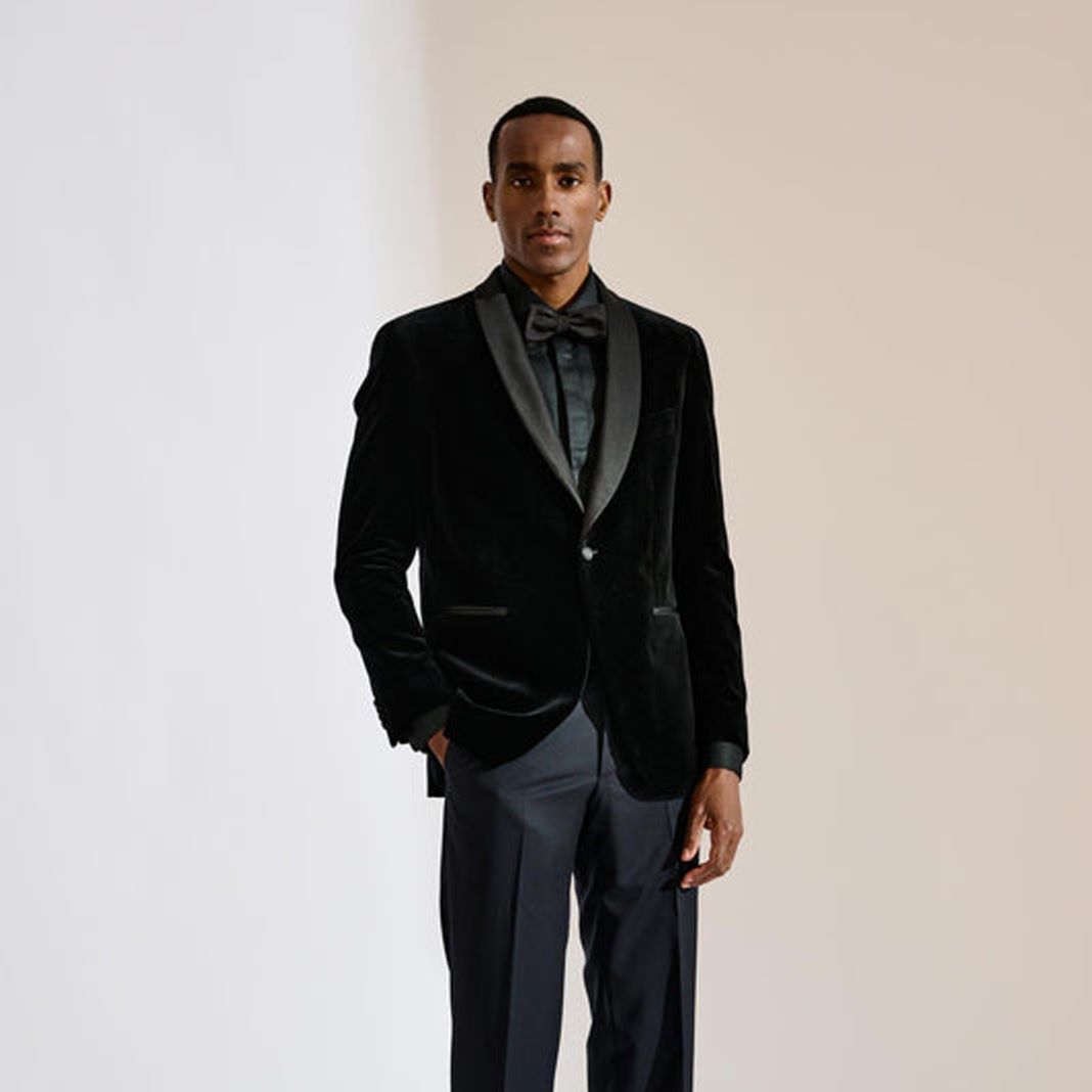 Black velvet dinner suit with a shawl lapel, worn with a black tuxedo shirt and black bow tie.