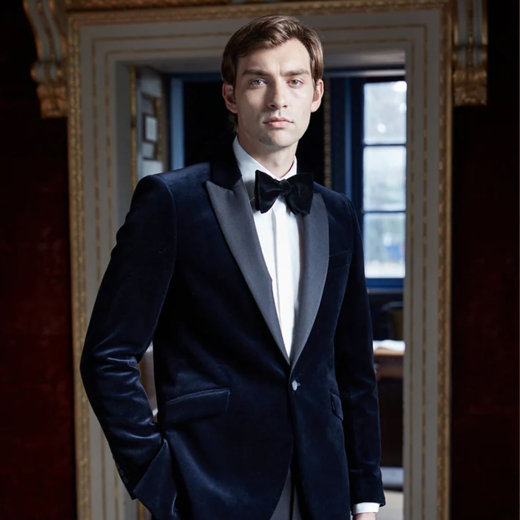 Navy blue velvet tuxedo with a peak lapel, paired with slim-fit black trousers