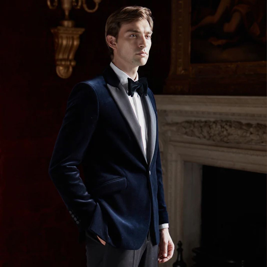 Classic velvet tuxedo in royal blue with a notch lapel, worn with black formal trousers.