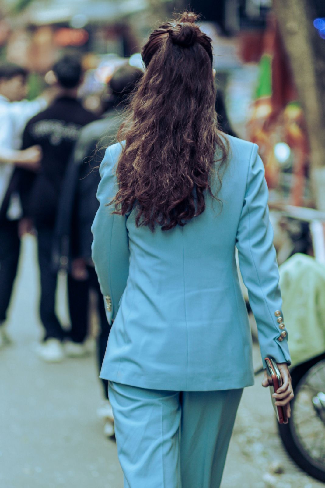 A light blue women’s suit shown from behind in a busy street, ideal for fashion week, influencer content, or promotional photography for modern tailored collections. - US