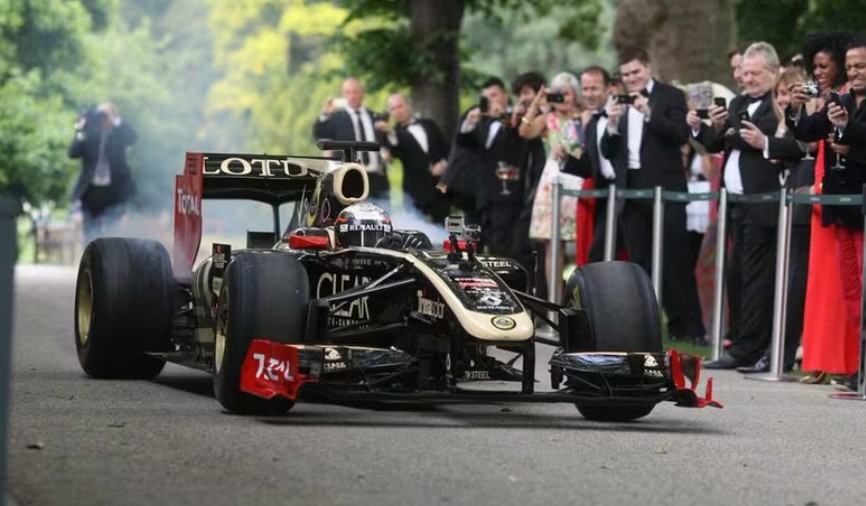 Formula 1 car arrives at the Grand Prix Ball 2025 as tuxedo-clad guests look on.