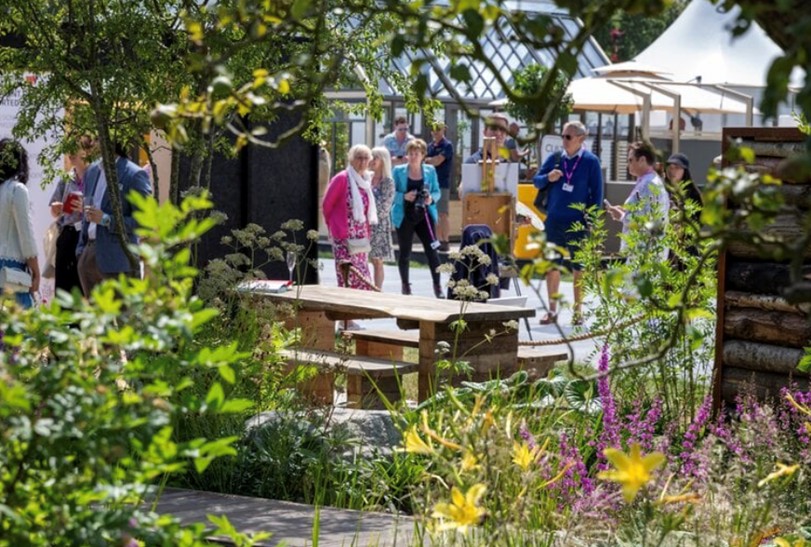 Visitors at the Hampton Court Garden Festival wearing smart casual summer outfits among flower displays and garden pavilions.</p>
<p>