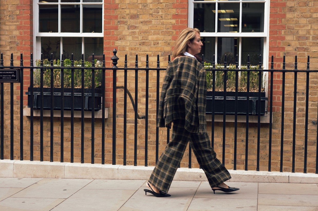 A woman dressed in tweed walking down the street