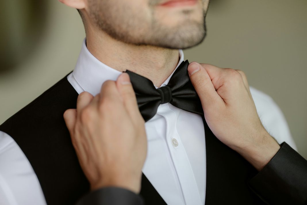 a photo of a self bow tie being put on a man who is getting dressed for a formal evening dinner