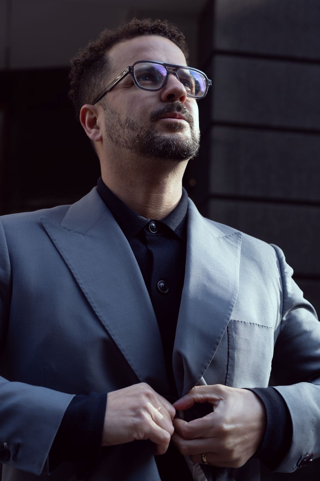 A photo of a man buttoning up his jacket because its chilly