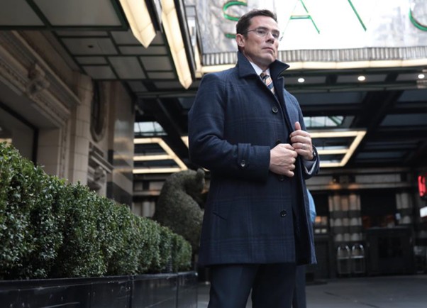 A photo of a man dressed in a suit with an overcoat which acts as a smart layer for colder weather.