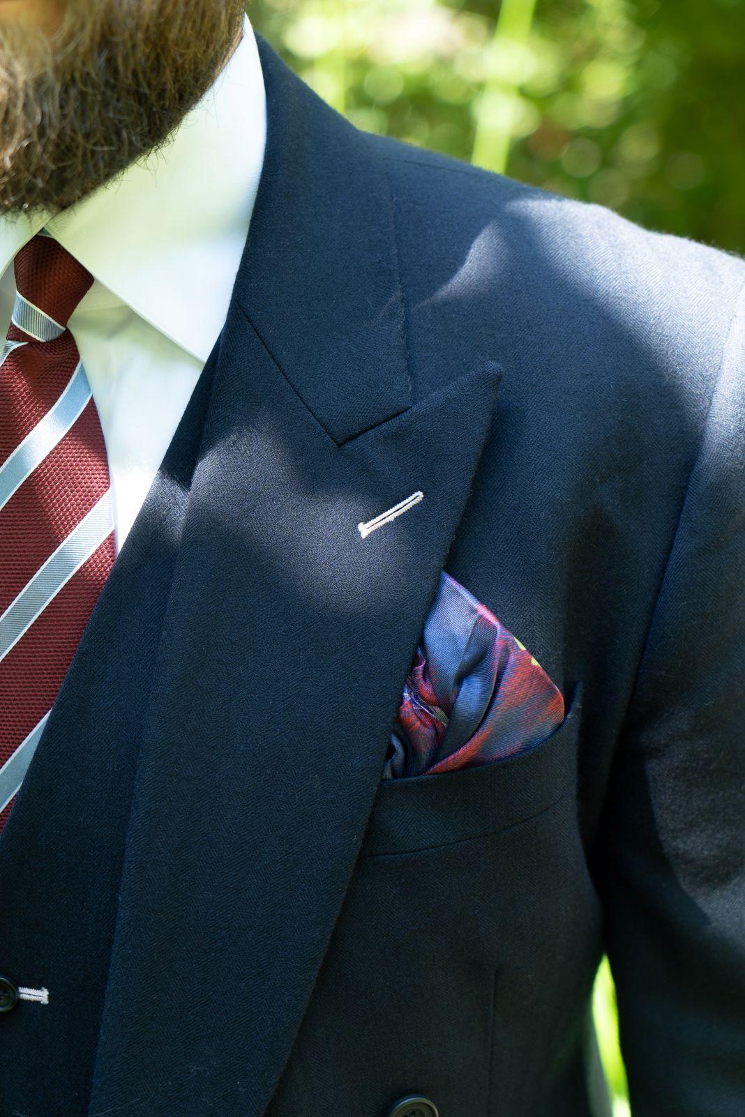 A photo of a navy suit with a striking pocket square and red and white tie