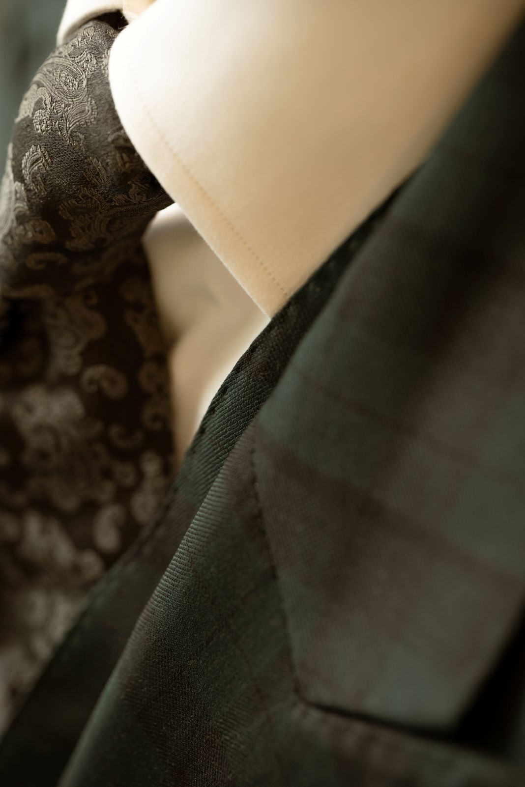 a close up photo of a check green suit and a black patterned tie