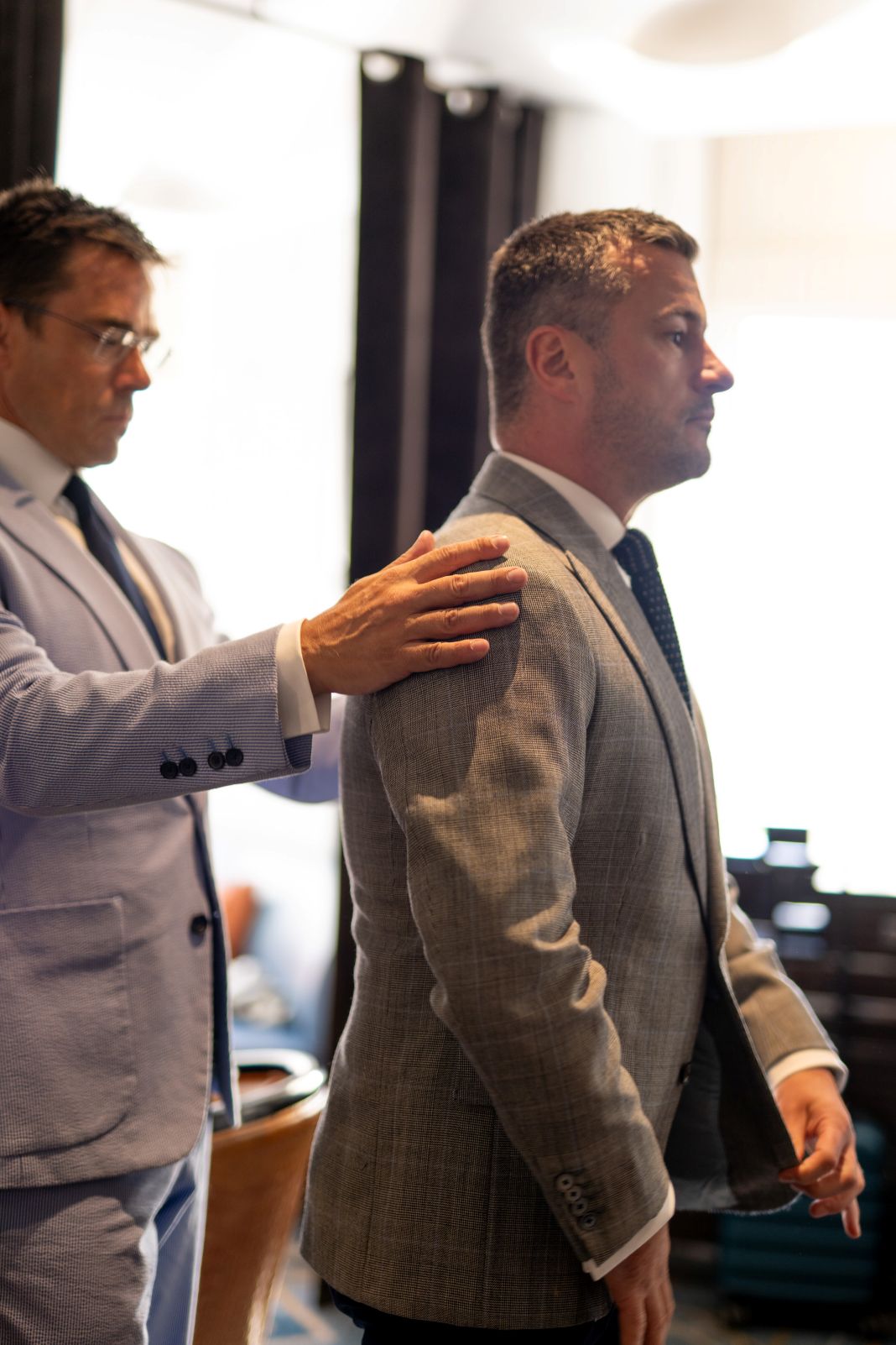a photo of a tailor checking a suit for a clients fitting