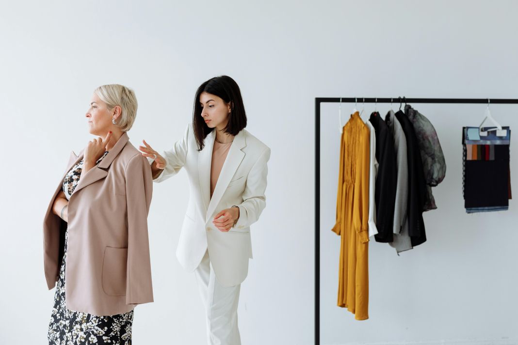 A photo of a female tailor making adjustments to her clients jacket