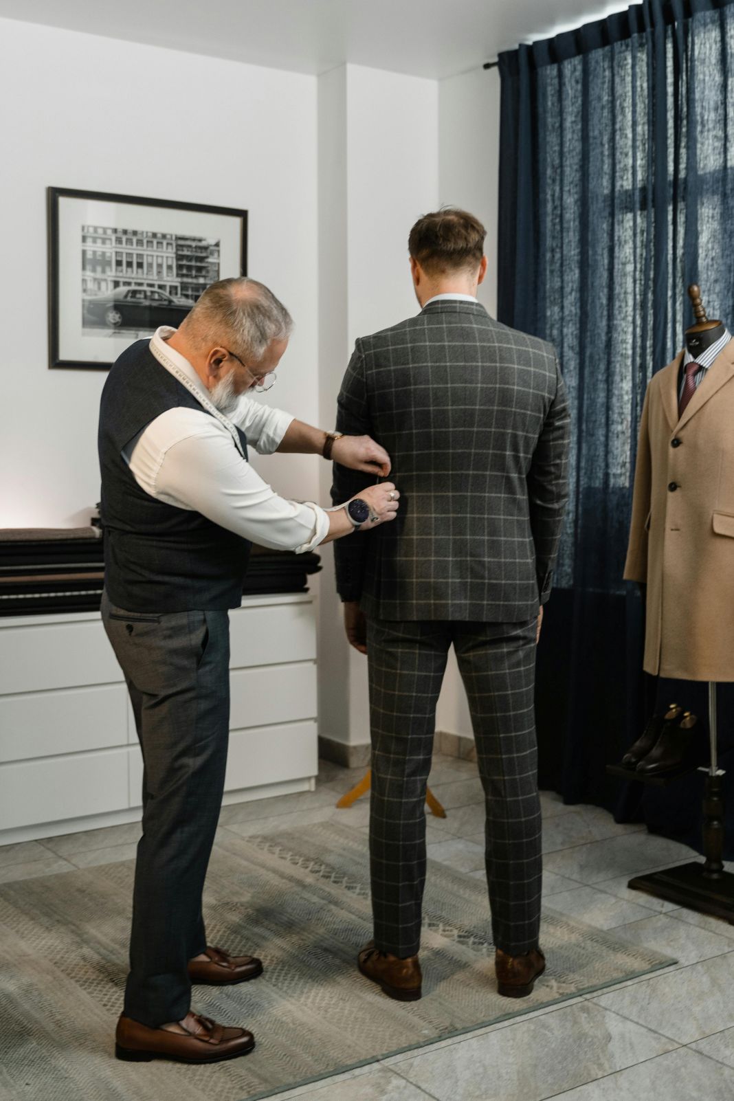 A photo of a tailor measuring for adjustments to his clients suit