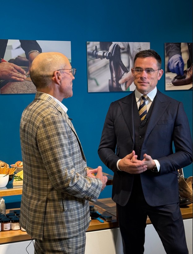Two men discussing fabric and fit inside a tailoring atelier, showcasing bespoke craftsmanship and suit styling
