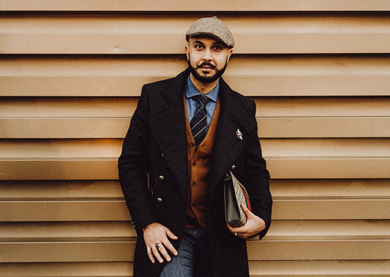 A vintage-inspired outfit with a tweed cap, layered suit, and smart accessories, blending classic British style.