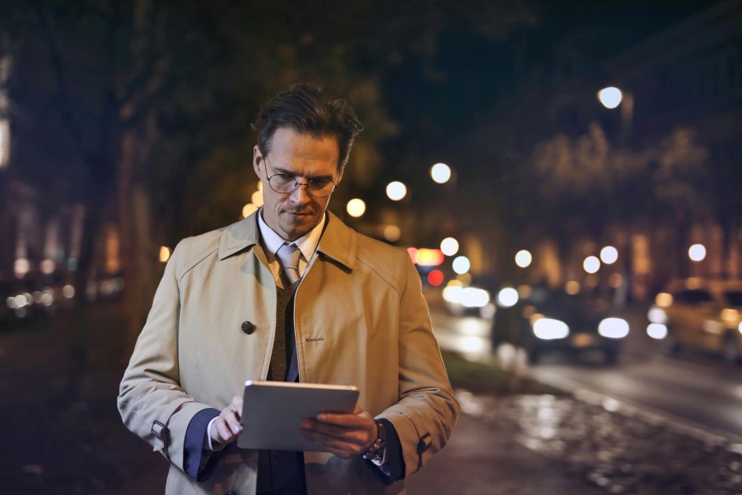 a photo of a business man standing in the street using a tablet wearing a smart coat