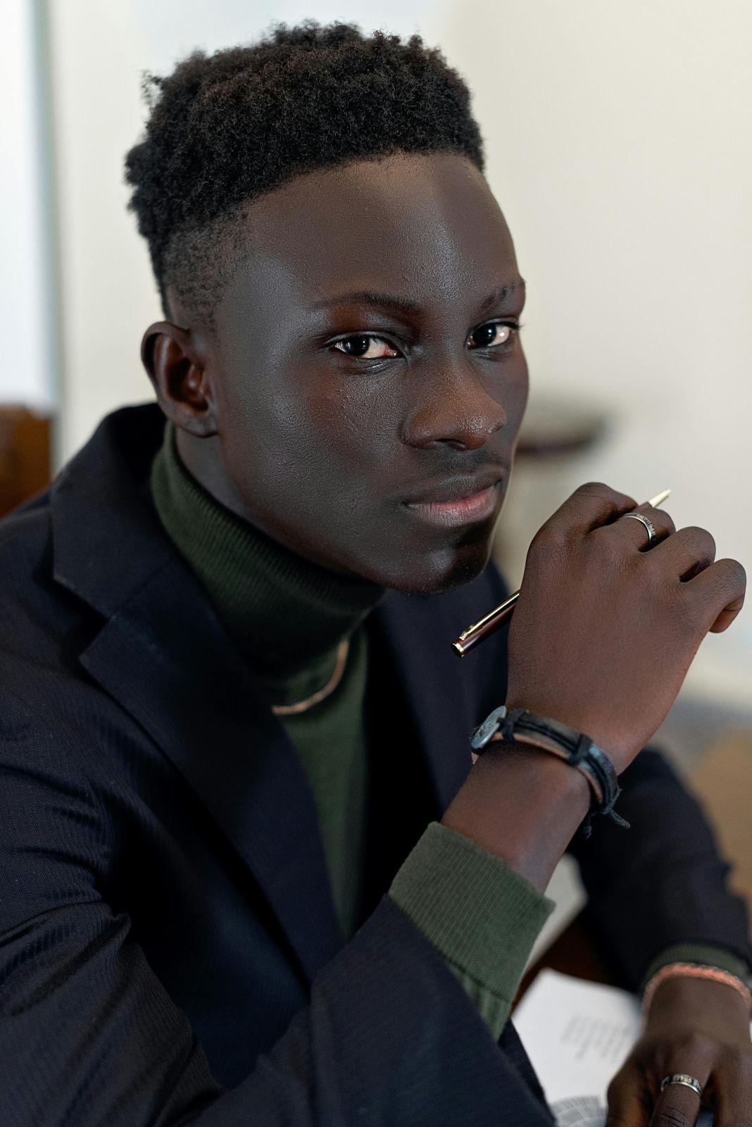 a photo of a man wearing a green roll neck underneath a navy blazer