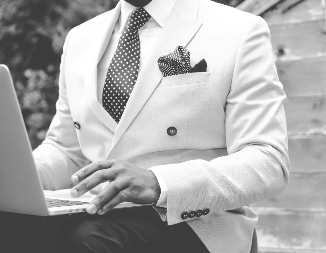 A black and white photo of a man working in a tailored suit