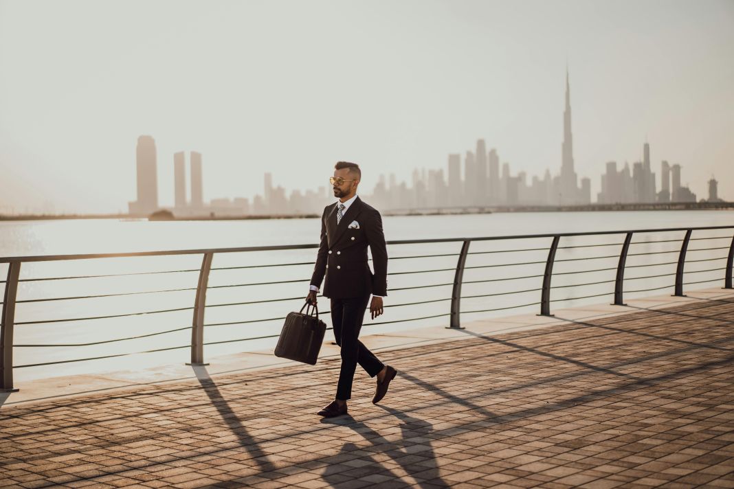 A photo of a man walking in a warm city in a bespoke suit
