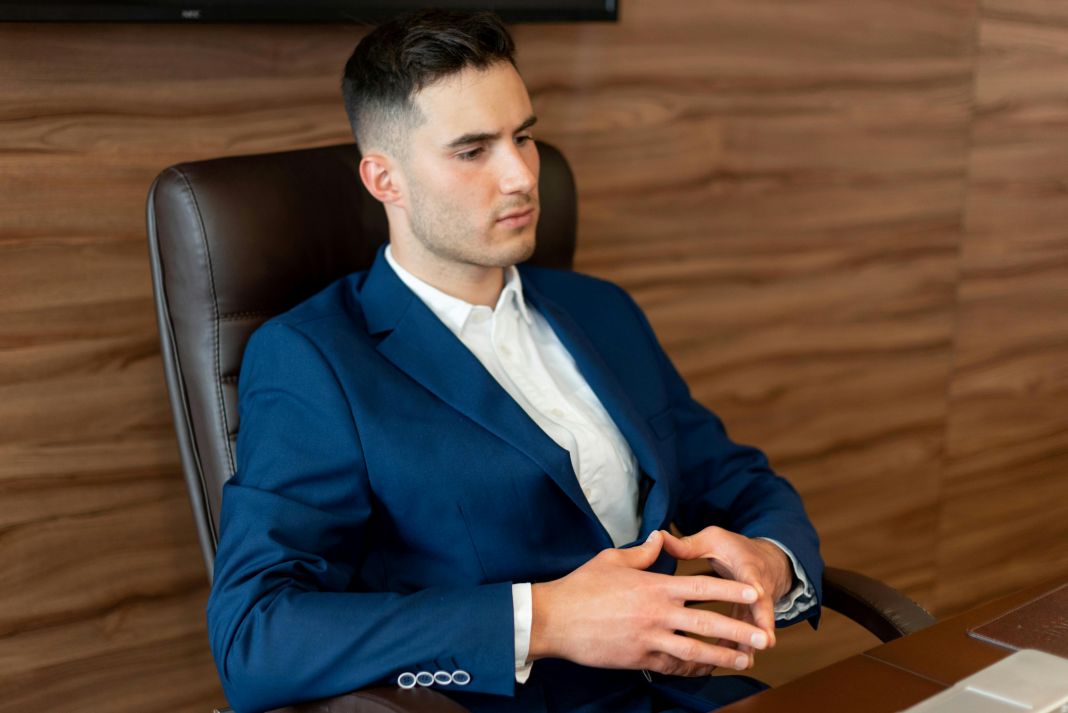 A photo of a man working in a hot office ina bespoke suit