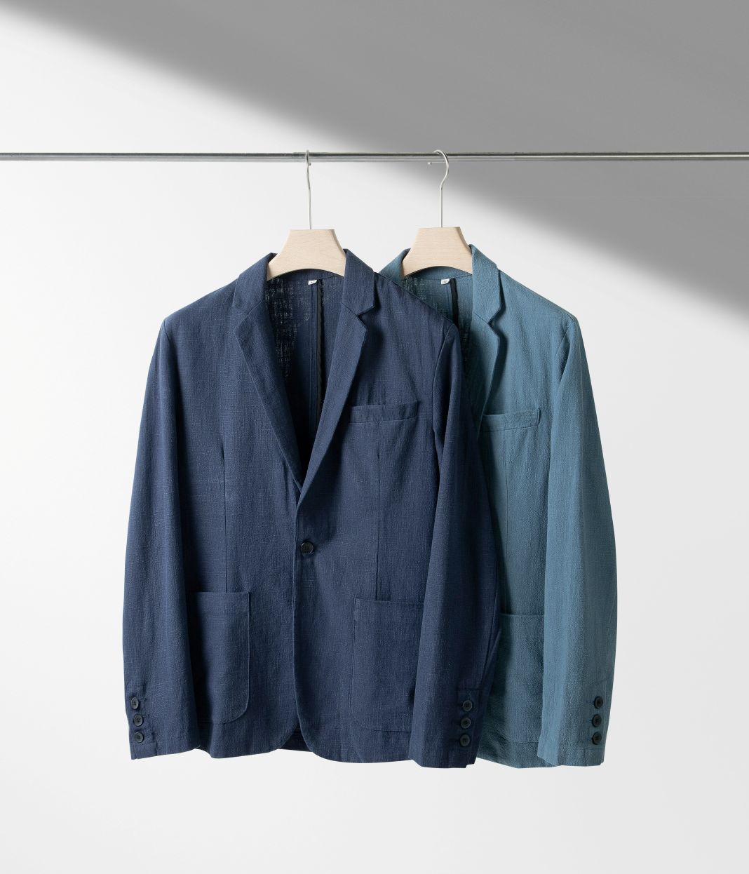 A photo of two lightweight suits hanging on a rail