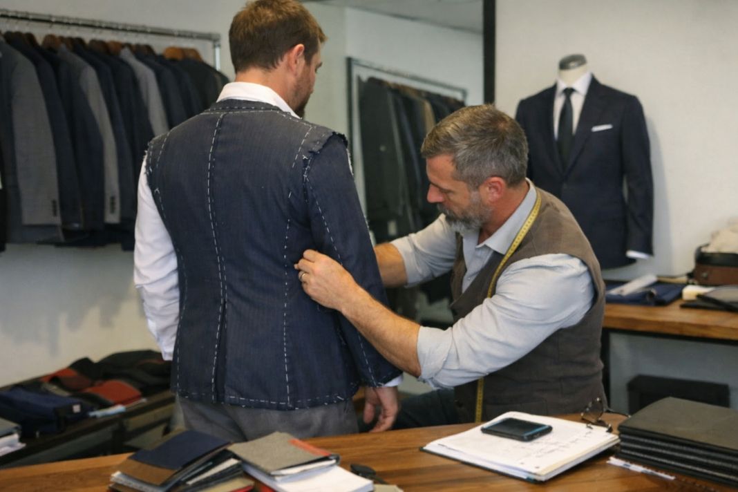 an illustrative photo of a tailor measuring a client for a wedding suit