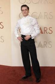 A photo of a person wearing a tailored white shirt and black trousers on the red carpet at the oscars