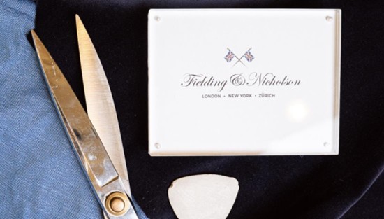 A photo of luxury bespoke tailors logo with cutting scissors and cloth