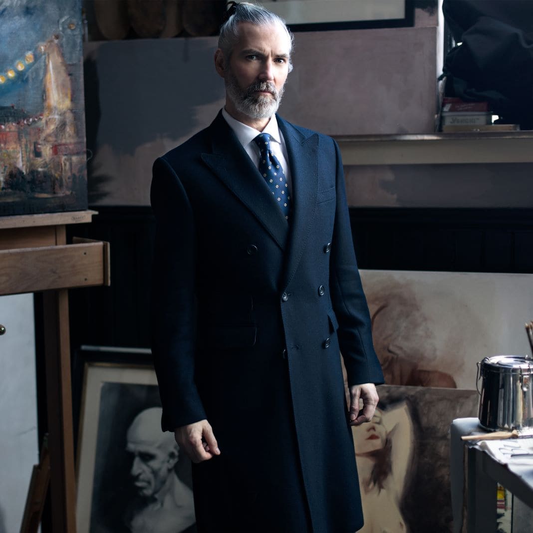 Black tailored overcoat worn over a suit and tie, sample image