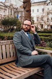 a photo of a well dressed gentleman in london sitting on a park bench
