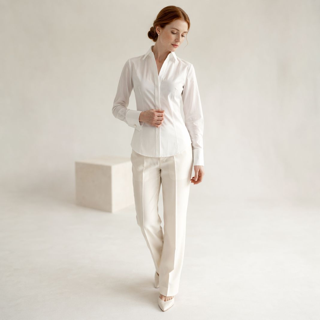 White tailored button-up blouse worn with slim-fit trousers