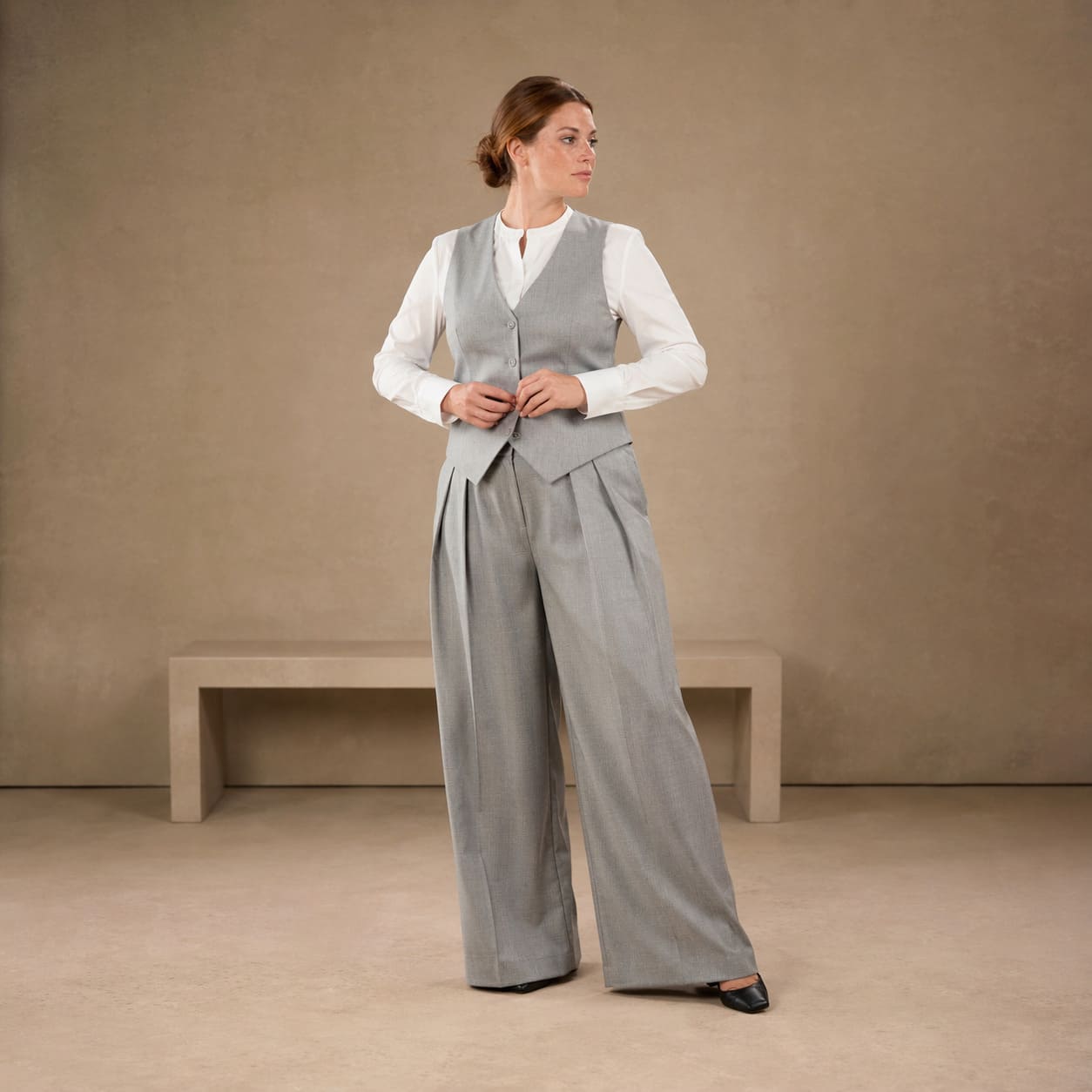White blouse worn with high waisted grey wide leg trousers