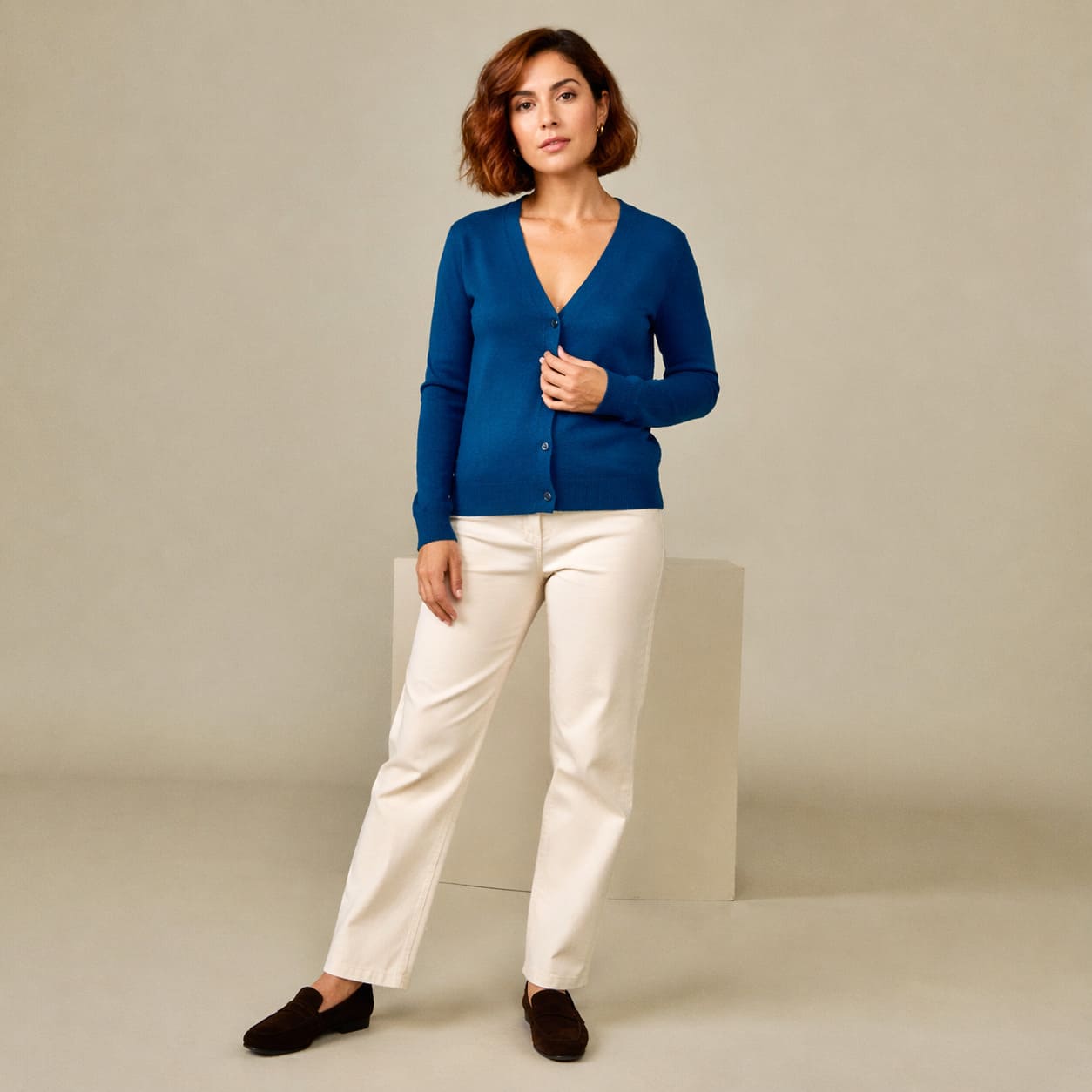 Blue knit sweater worn with cream straight-leg trousers, sample image
