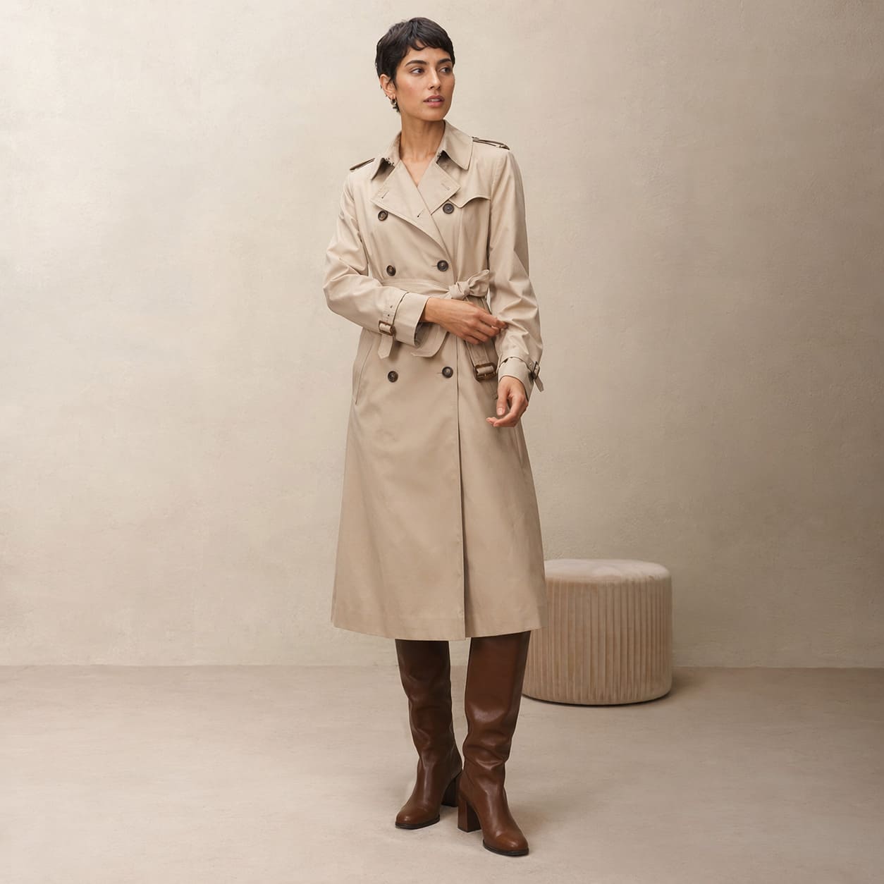 Woman in a beige knee length trench coat with a belt detail, sample image