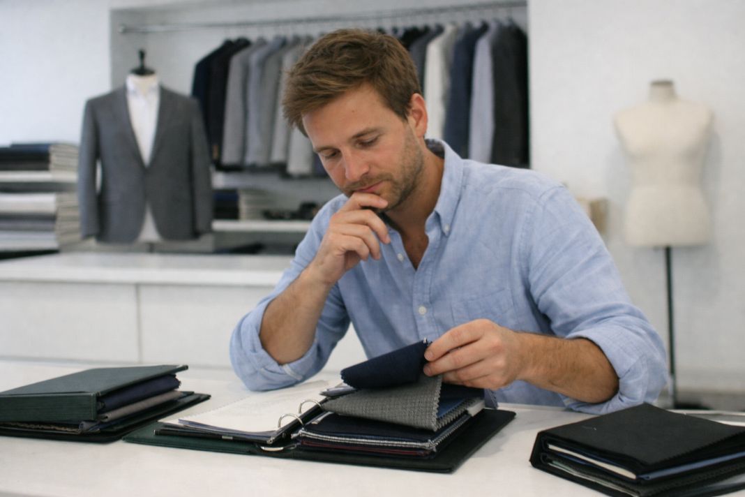 an illustrative photo of a man choosing fabrics at a bespoke tailors in London