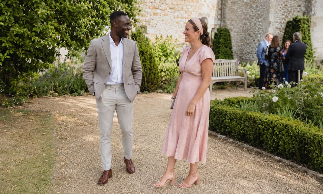 A lightweight stone linen suit styled with a white shirt complements a soft blush pink midi dress, offering refined and comfortable summer christening outfits suitable for garden ceremonies and family occasions. A lightweight stone linen suit styled with a white shirt complements a soft blush pink midi dress, offering refined and comfortable summer christening outfits suitable for garden ceremonies and family occasions.
