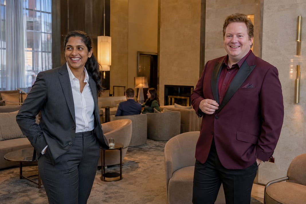 A charcoal tailored trouser suit with an open-collar shirt is paired alongside a burgundy blazer with dark tailored trousers, showcasing bespoke tailoring that embraces different personalities, body proportions, professional wardrobes and individual style preferences.