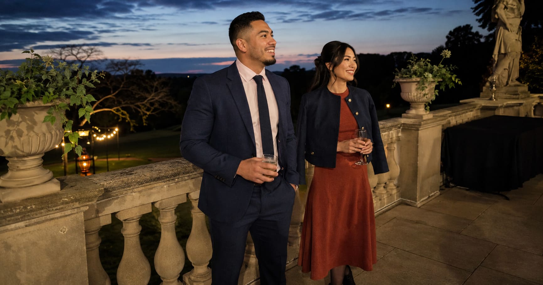 Man wearing navy suit and woman wearing rust dress attend an outdoor autumn wedding. Man wearing navy suit and woman wearing rust dress attend an outdoor autumn wedding.