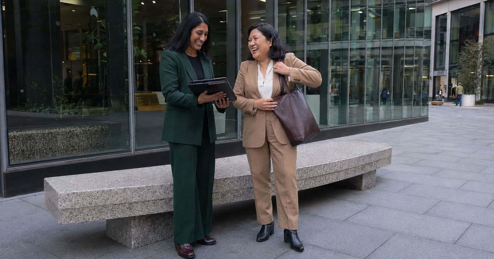 Women wearing forest green and blush tailoring walk through London in modern autumn style.
