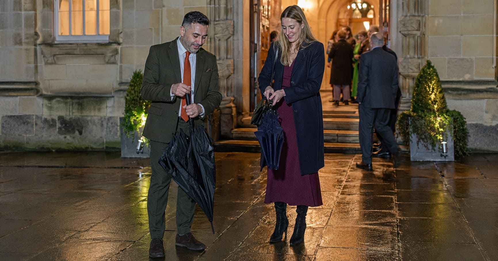 Women wearing navy, burgundy and mustard tailoring attend a colourful autumn city event together.