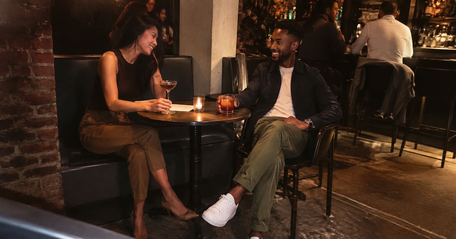 Couple seated at an bar in smart casual layers Couple seated at an bar in smart casual layers