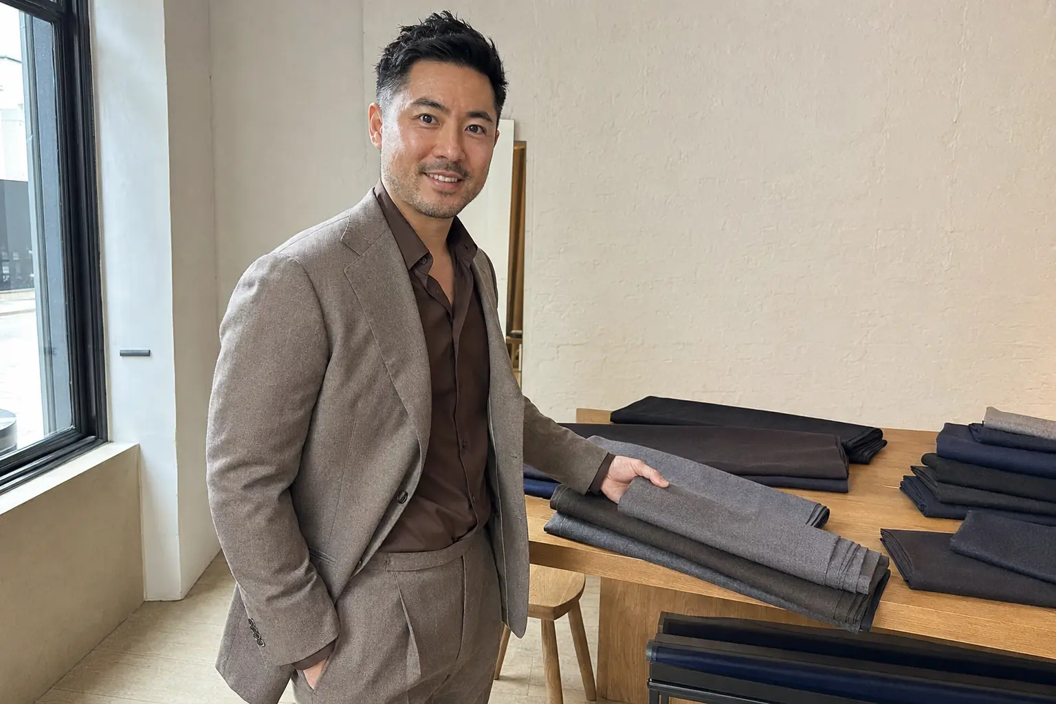 Customer comparing stone made to measure suit fabrics inside modern London showroom