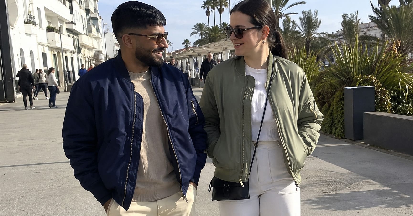 Man in navy jacket and woman in sage jacket walking together Man in navy jacket and woman in sage jacket walking together