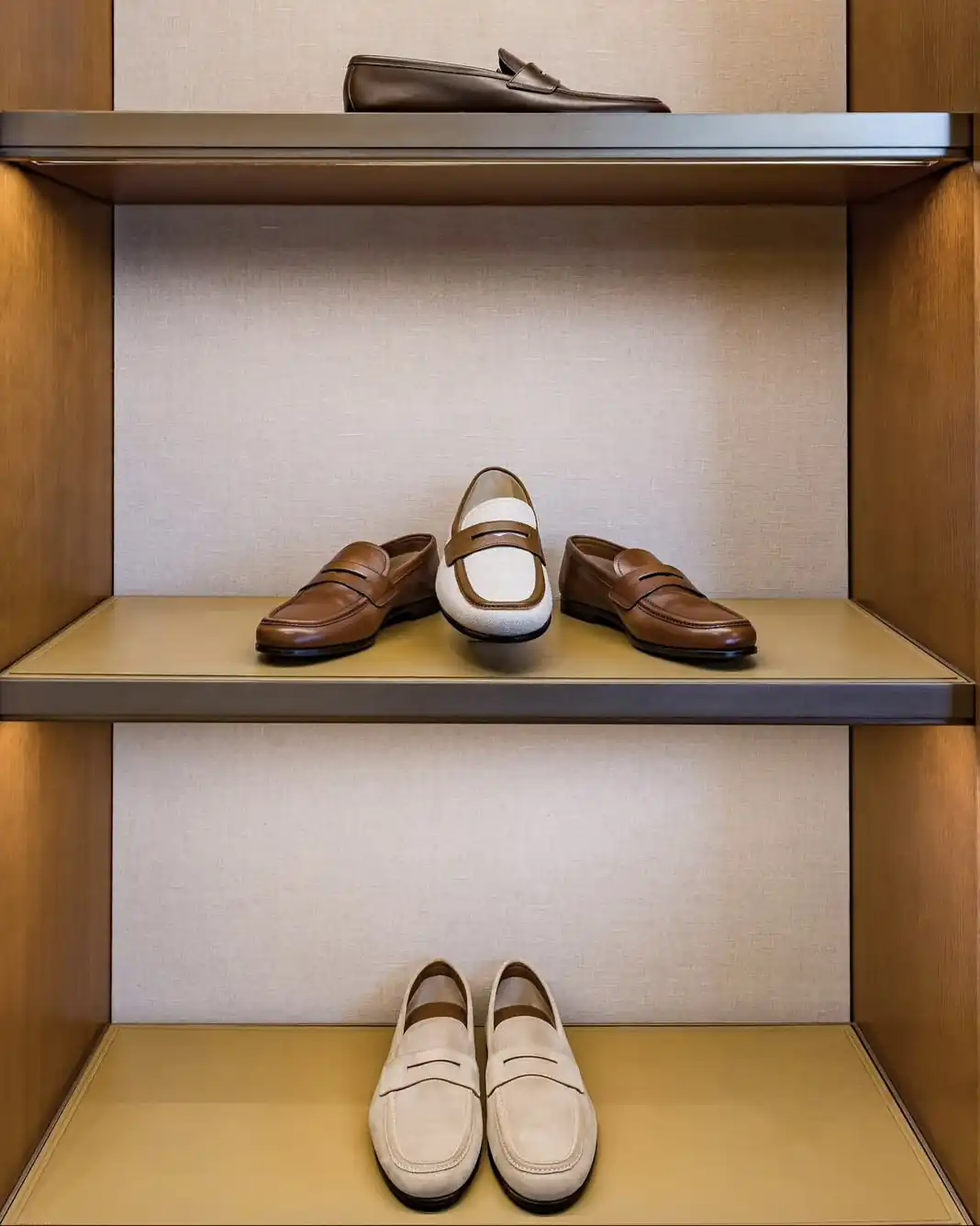 Brown and cream leather loafers on lit wooden display shelves