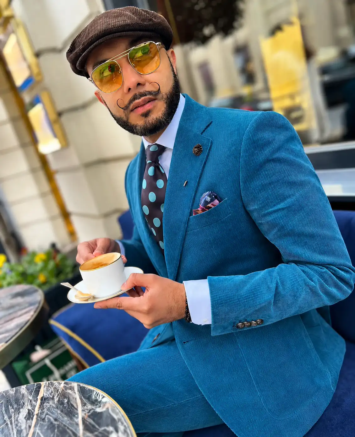 Teal corduroy suit with a blue polka dot tie and a patterned pocket square